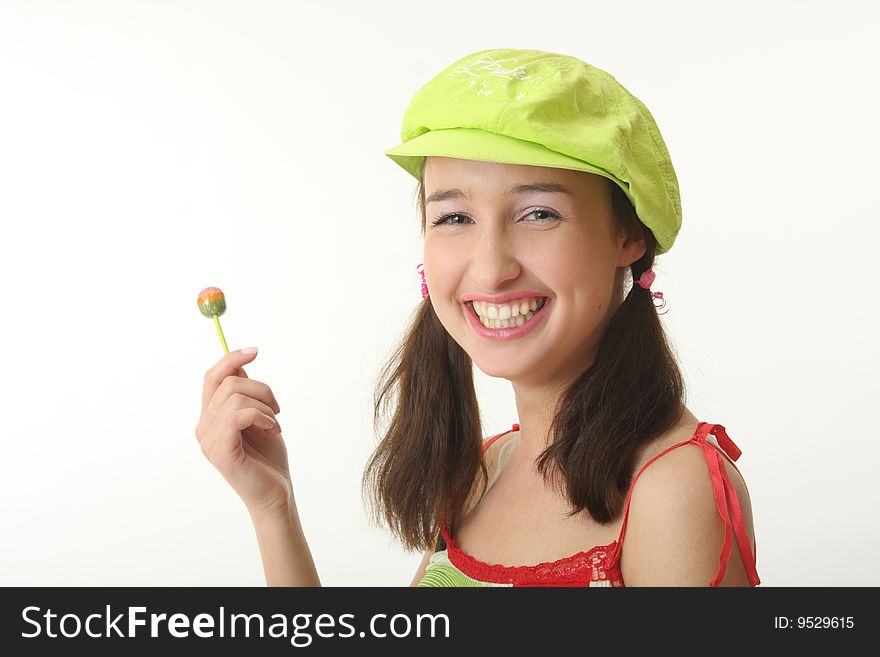 The girl in a green cap eats a sugar candy