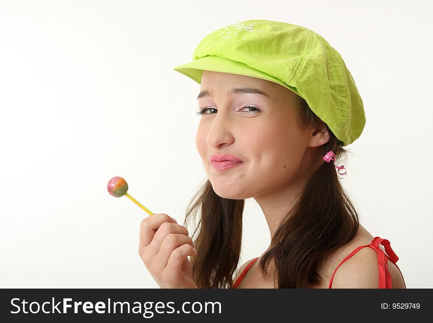 The girl in a green cap eats a sugar candy