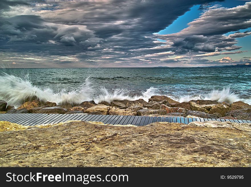 Waves hitting breakwater in cloudy day