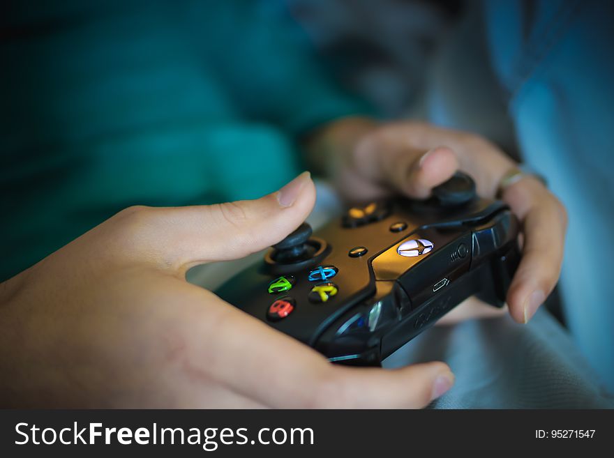 A close up of hands holding a video game controller. A close up of hands holding a video game controller.