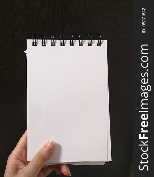 A close up of a hand holding a blank notebook. A close up of a hand holding a blank notebook.