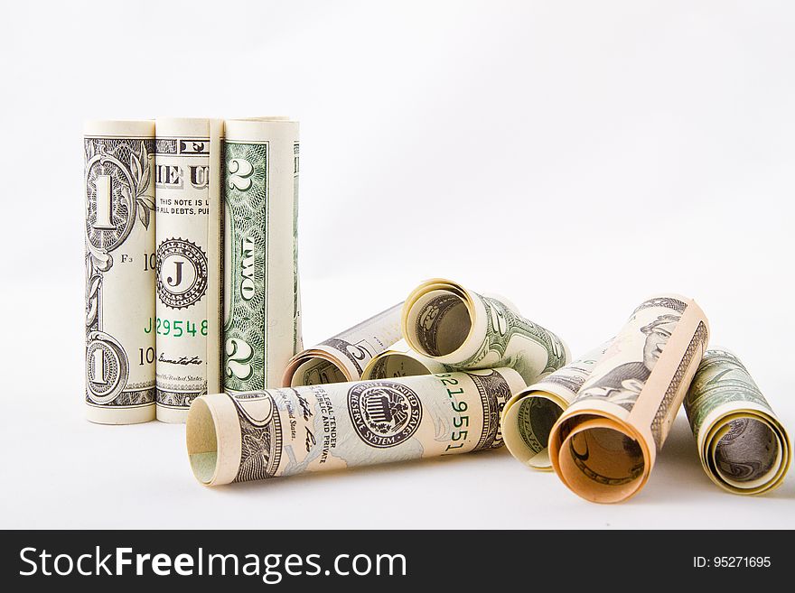 A close up of rolled dollar bills on a white background.