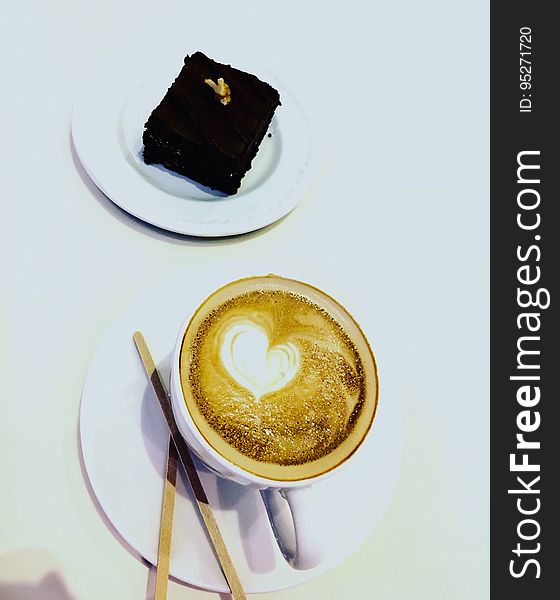 A cup of cappuccino and a piece of chocolate brownie cake. A cup of cappuccino and a piece of chocolate brownie cake.