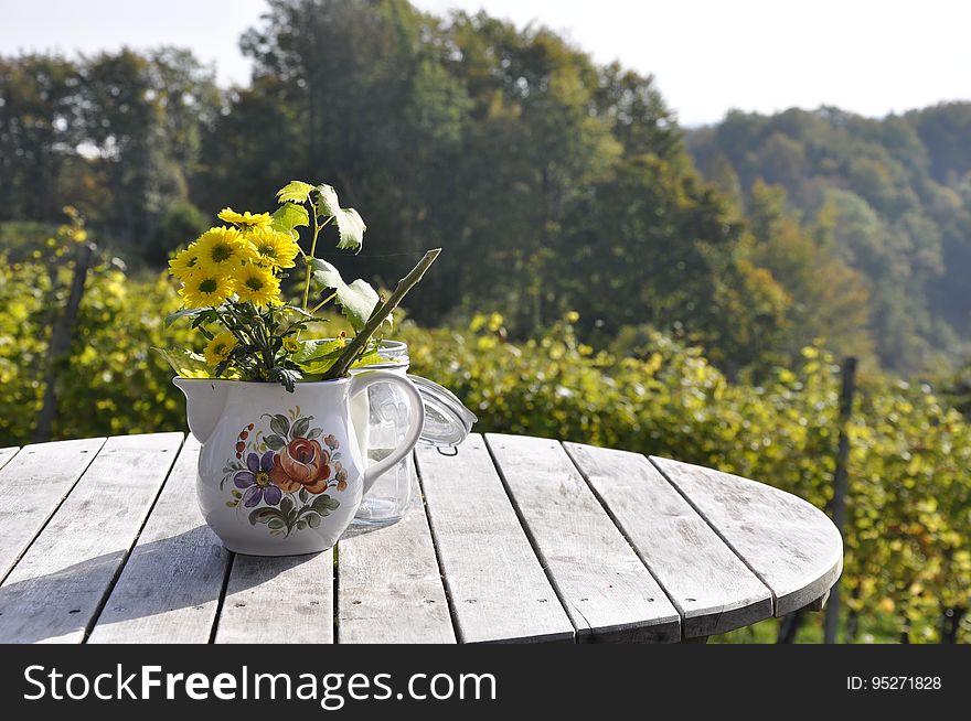 Decorative yellow flowers in a teapot on a wooden table. Decorative yellow flowers in a teapot on a wooden table.