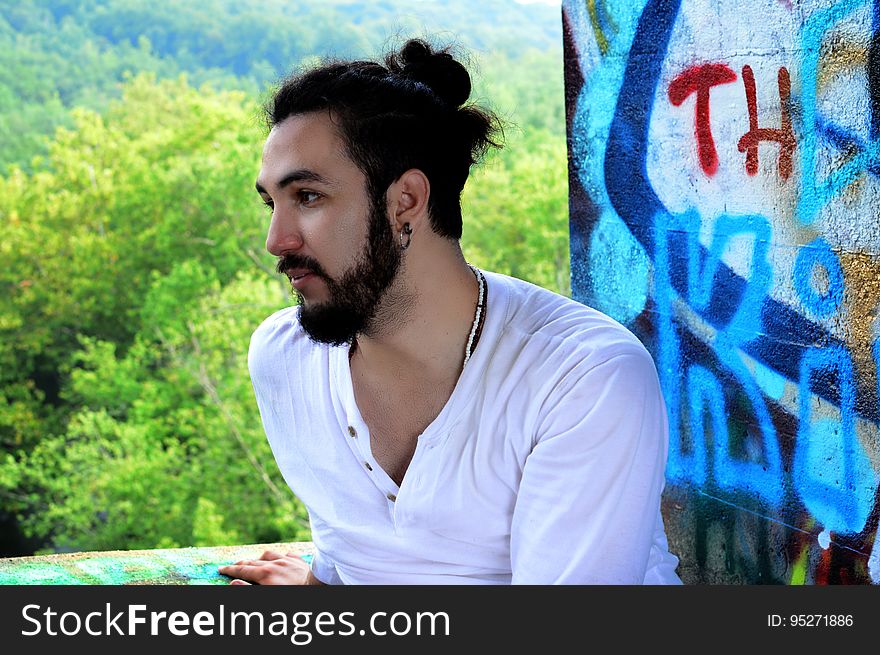 A man sitting in front of a wall with graffiti. A man sitting in front of a wall with graffiti.