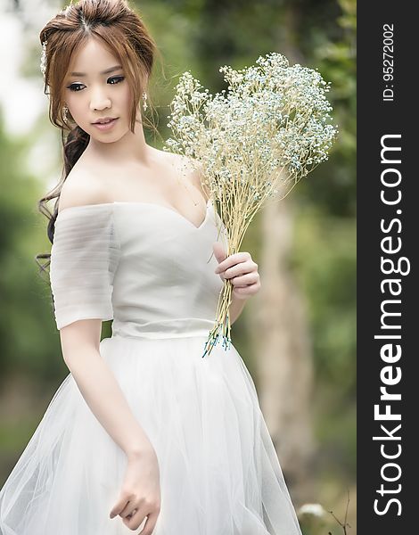 An Asian woman in bridal gown with a bouquet of wild flowers. An Asian woman in bridal gown with a bouquet of wild flowers.