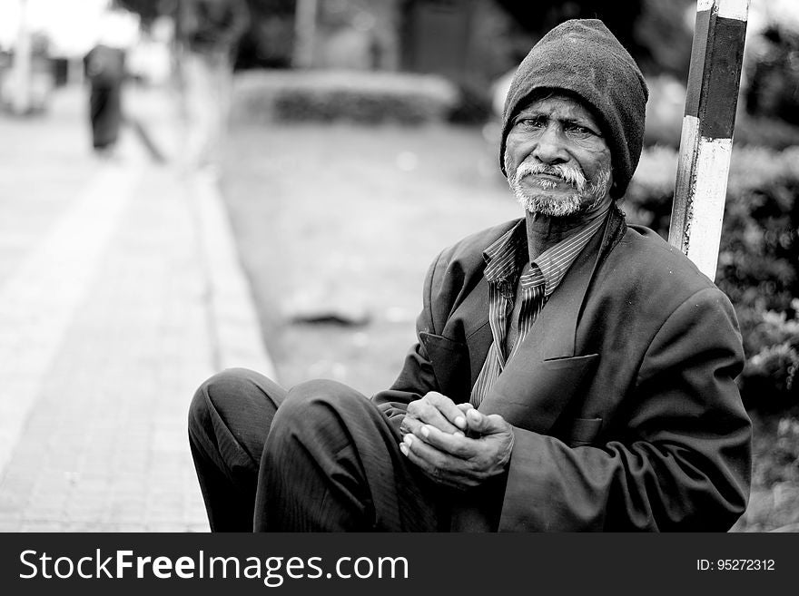 Black and white portrait of sad homeless old man sat in street. Black and white portrait of sad homeless old man sat in street.