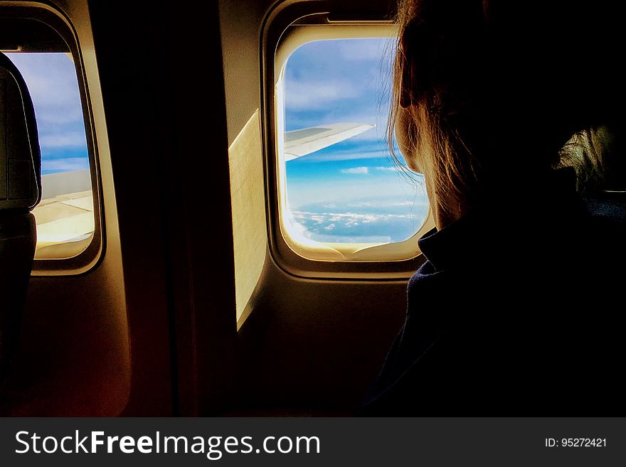 A woman looking through an airplane window. A woman looking through an airplane window.