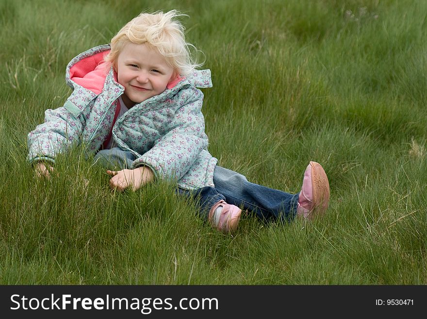 Young girl grinning after falling in long grass