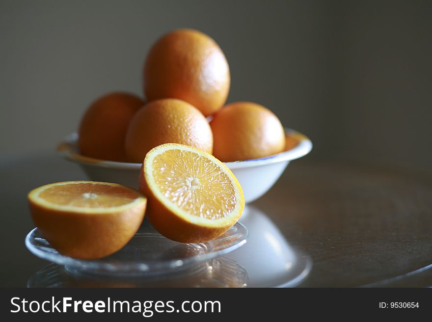 Sliced oranges on a plate with oranges in a bowl in background.