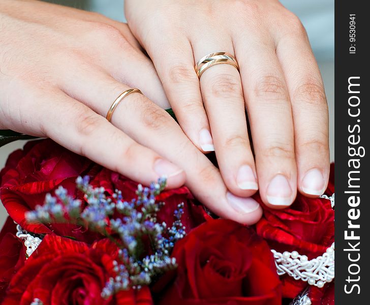 Hands of a couple with wedding rings on a bride's bouquet. Hands of a couple with wedding rings on a bride's bouquet