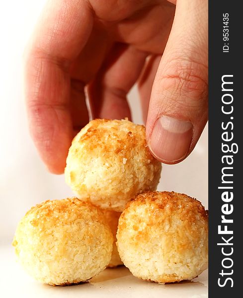 Clean coconut balls on a shiny plate with white background, one held by a hand. Clean coconut balls on a shiny plate with white background, one held by a hand