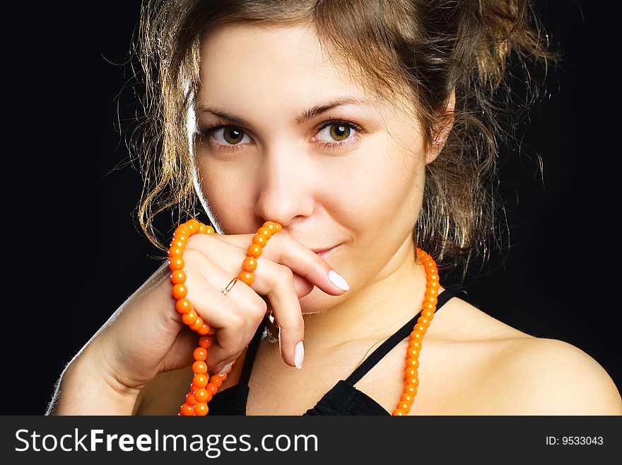 Studio portrait of a beautiful young brunette woman with orange beads. Studio portrait of a beautiful young brunette woman with orange beads