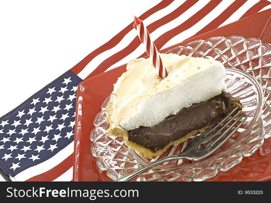 A pie of homemade chocolate meringue pie with one candle on an american flag background, horizontal with copy space. A pie of homemade chocolate meringue pie with one candle on an american flag background, horizontal with copy space