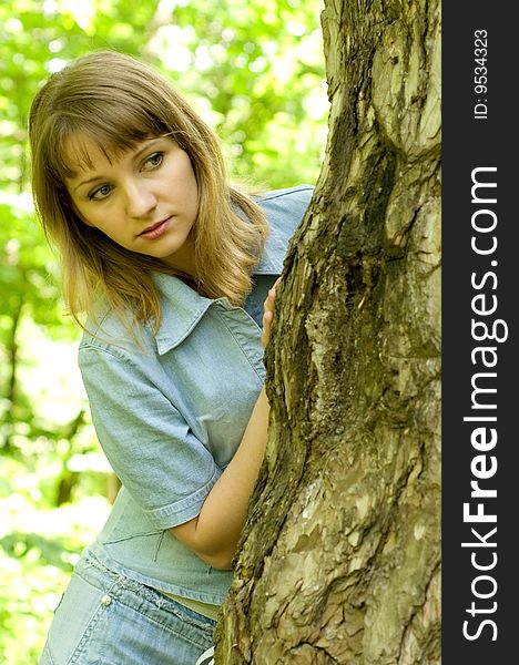 The beautiful girl in park to stand near an old tree. The beautiful girl in park to stand near an old tree