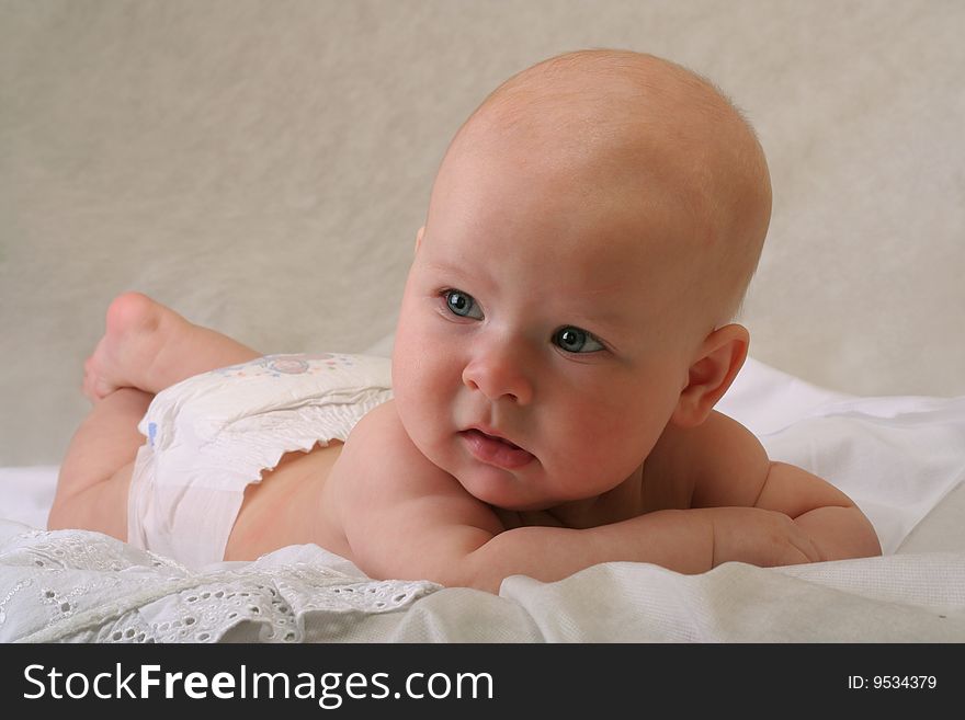Serious 5 months old baby girl with diaper on white background