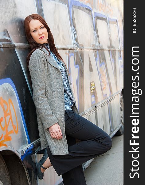 Sad young woman stands near wall with graffiti