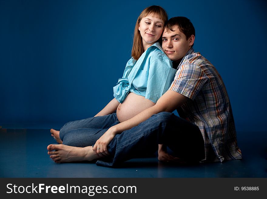 Beautiful couple waiting baby over blue