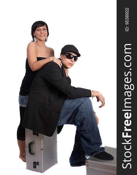 Young stylish couple isolated over white. He is sitting on dj cases. Young stylish couple isolated over white. He is sitting on dj cases.