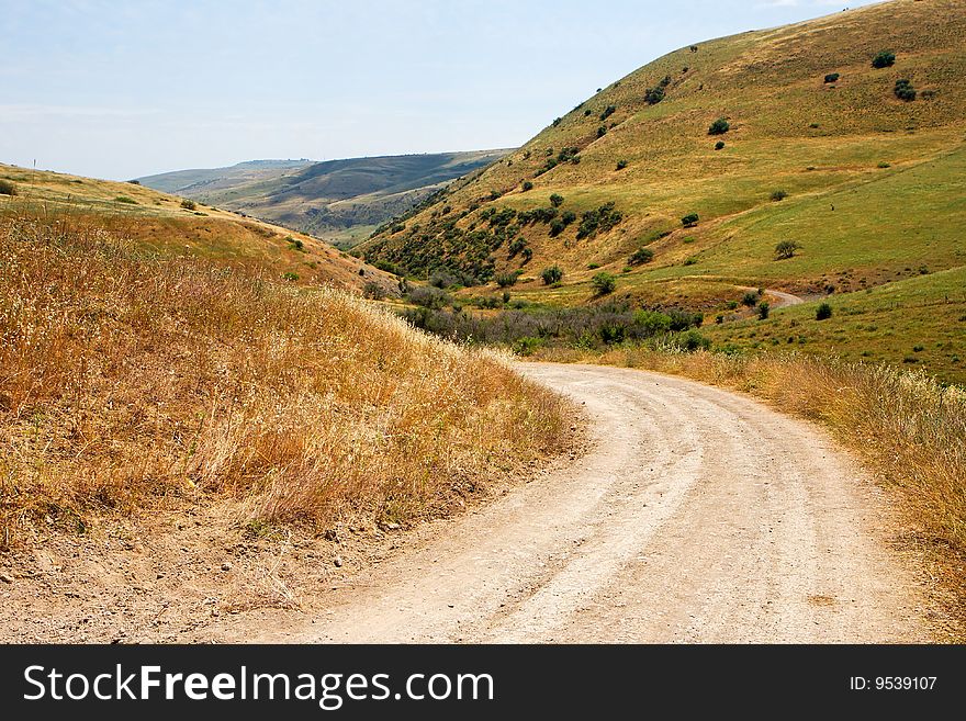 Countryside road bends among yellow autumn hills