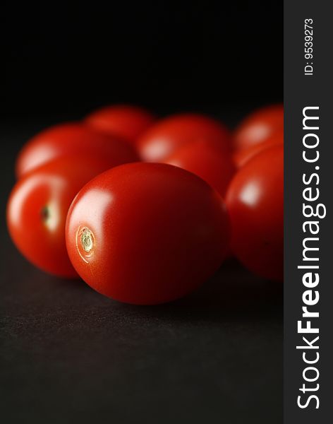 A small group of tomatoes background on black. A small group of tomatoes background on black