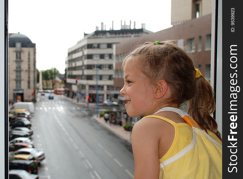 Smiling little girl at open window in town.