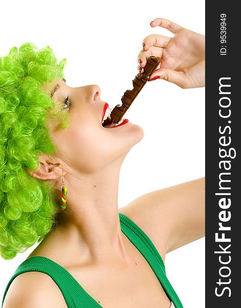 Closeup of an attractive woman with green wig biting a chocolate bar