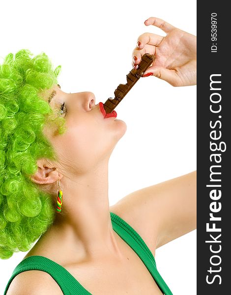 Closeup of an attractive woman with green wig sucking on a chocolate bar