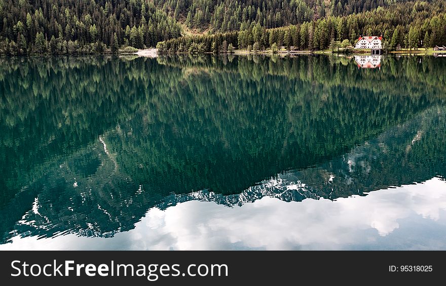 A mountain range and conifer forest reflection on the surface of water. A mountain range and conifer forest reflection on the surface of water.