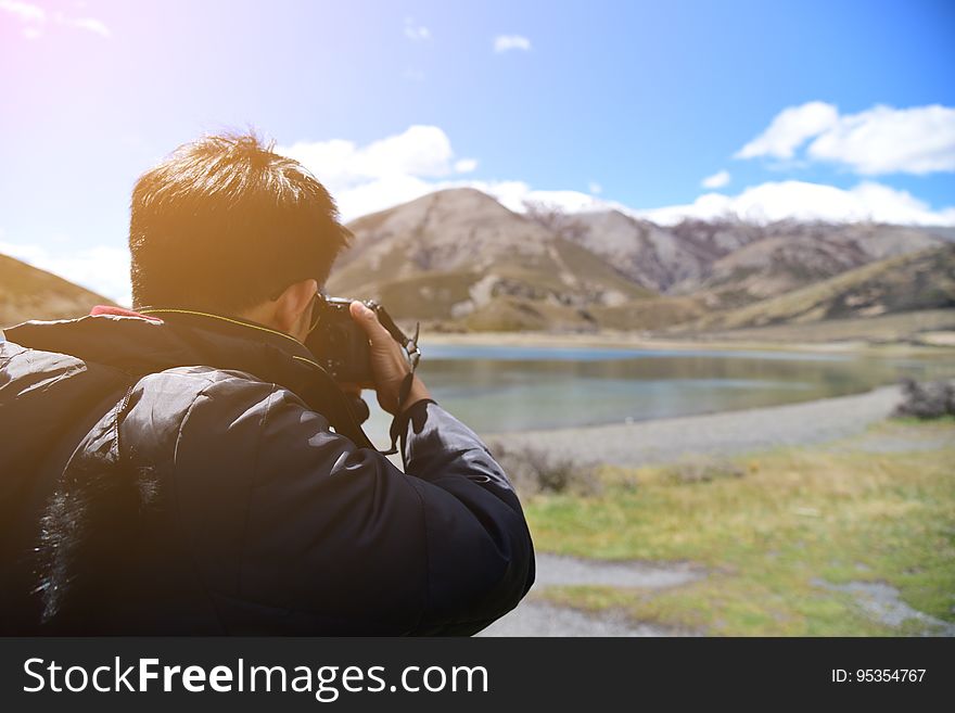 A photographer taking a photo of a mountain landscape. A photographer taking a photo of a mountain landscape.