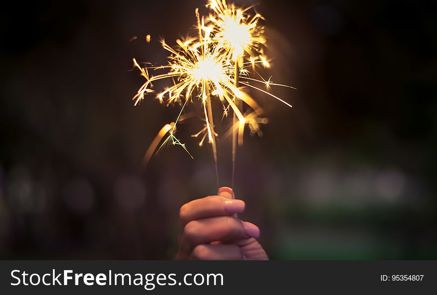 A close up of a hand holding a pair of sparklers. A close up of a hand holding a pair of sparklers.