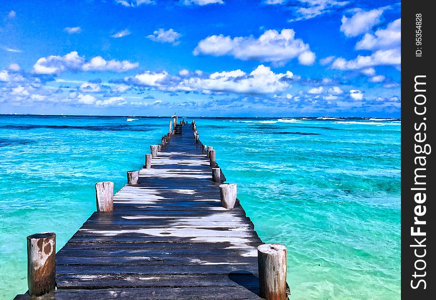 Wooden dock reaching into blue Caribbean waters on sunny day with blue skies. Wooden dock reaching into blue Caribbean waters on sunny day with blue skies.