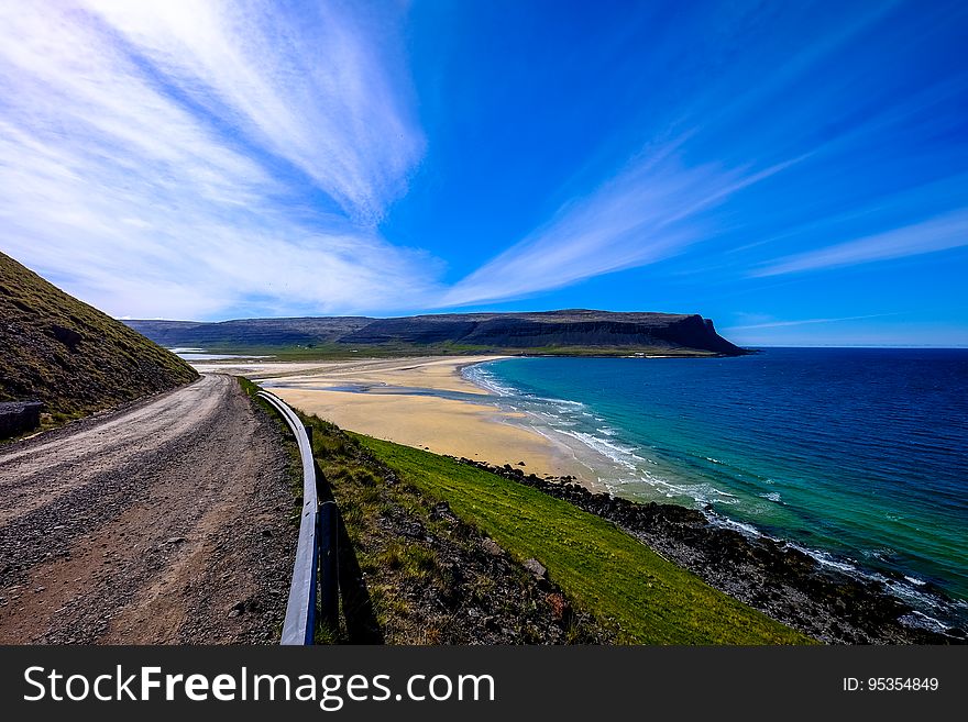 Aerial view of sandy beach along waterfront with blue skies on sunny day.