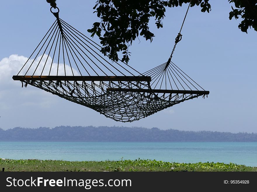 A hammock hanging on a beach and the coast in the background. A hammock hanging on a beach and the coast in the background.