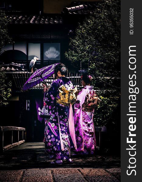 Asian women in colorful kimono robes and parasol standing on bridge in garden. Asian women in colorful kimono robes and parasol standing on bridge in garden.