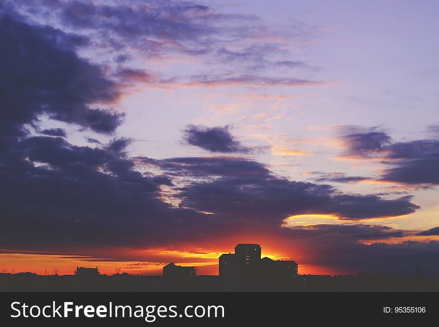 Houses silhouetted against sunset with blue skies.