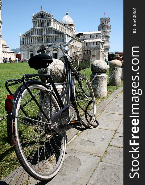 A bicycle in Pisa with a view of the leaning tower in the background