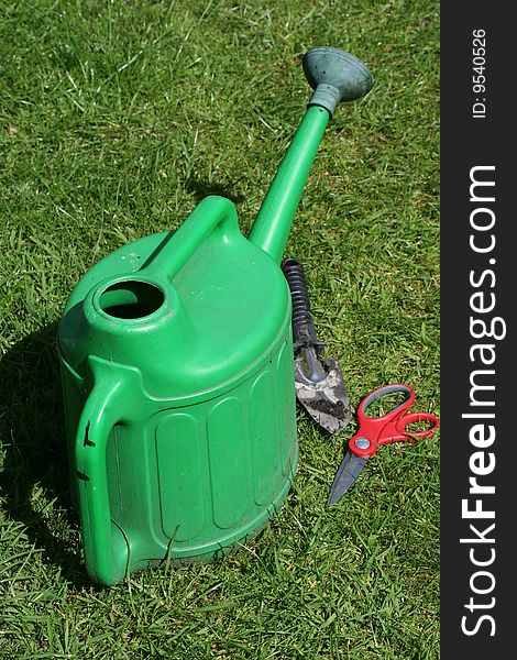 Watering can and tools on grass background with copy-space