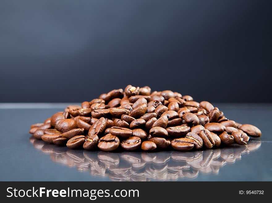Heap of coffee beans on a glass surface