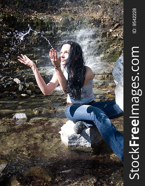 Woman plays with water near waterfall. Woman plays with water near waterfall
