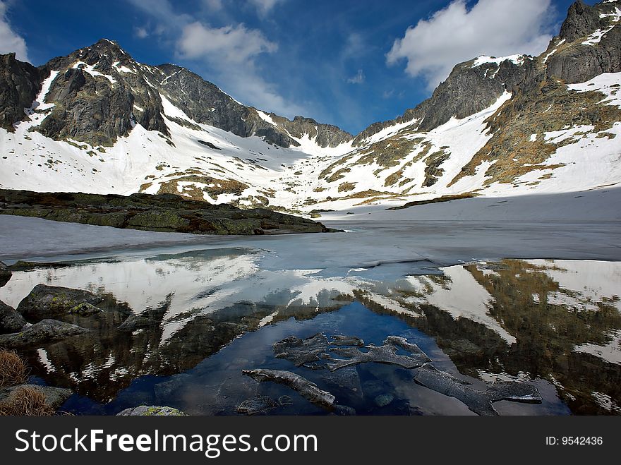 Melting lake among mountains with snow and mountains reflection. Melting lake among mountains with snow and mountains reflection