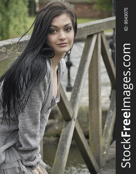 Young European pretty woman stands on the old wooden bridge alone and looks to the camera. Young European pretty woman stands on the old wooden bridge alone and looks to the camera