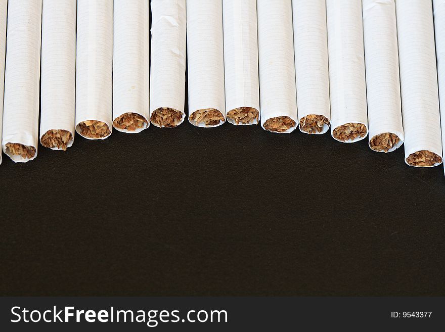 Close-up of row lying cigarettes isolated on black background
