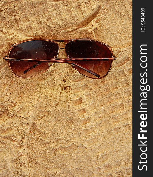 A background of brown sunglasses fallen on sand. A background of brown sunglasses fallen on sand