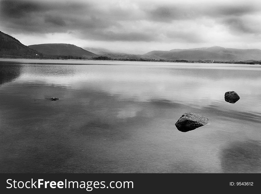 Rocks sitting in the calm waters of a lake in north Cumbria England. Rocks sitting in the calm waters of a lake in north Cumbria England