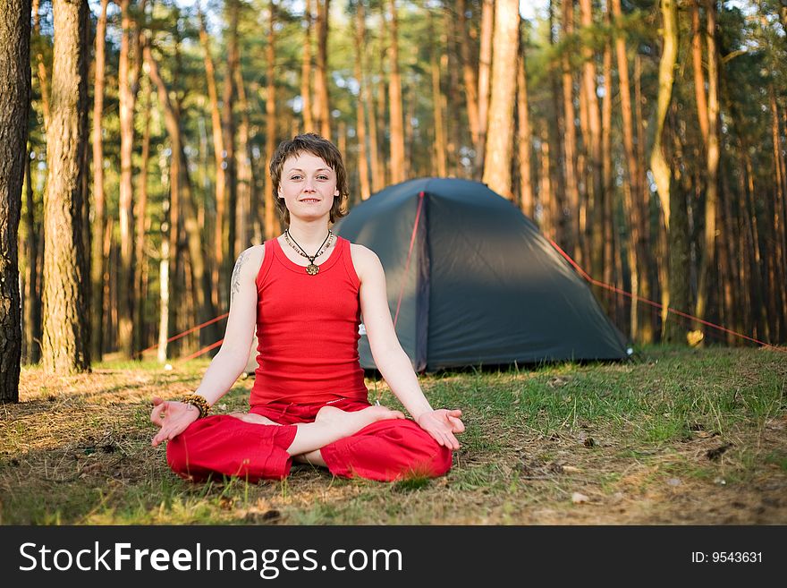 Pretty young woman relaxing in the forest in lotos pose