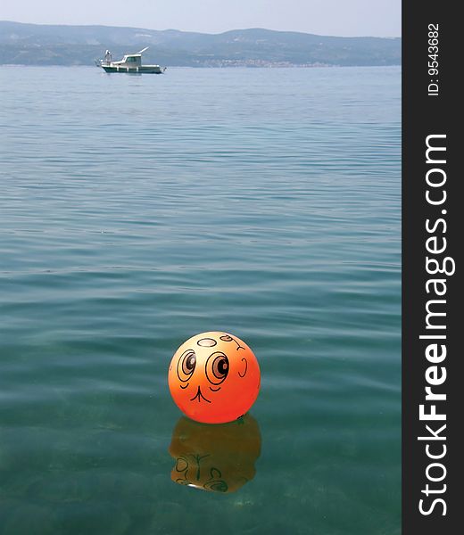 Funny ball on blue sea and boat. Funny ball on blue sea and boat