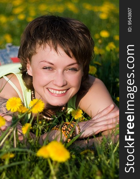 A young cheerful woman having fun on a dandelions glade