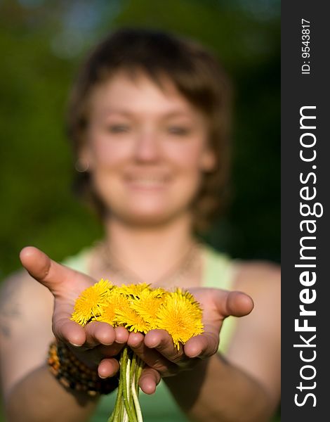 A young cheerful woman with a bunch of dandelions in her hands
