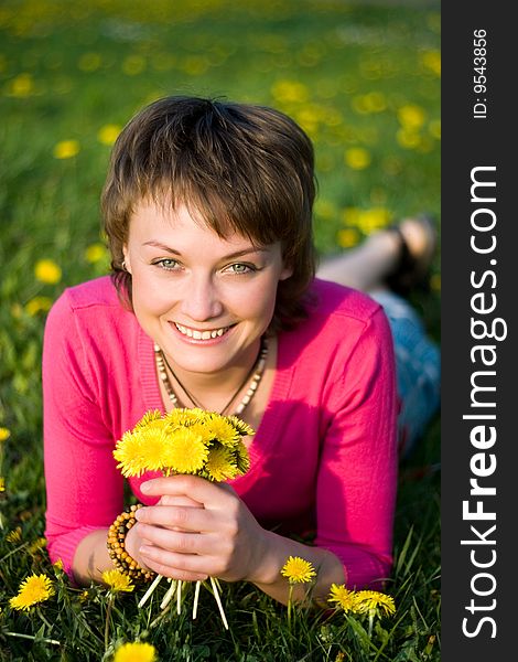 A young cheerful woman having fun on a dandelions glade